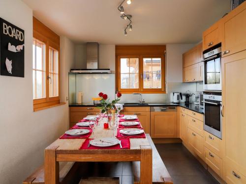 a kitchen with a wooden table with red napkins at Apartment La Corniche 2 by Interhome in Nendaz