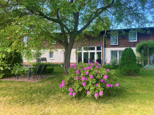 a house with pink flowers in the yard at Ferienhof Thur Mellenthin in Mellenthin