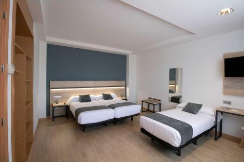 a hotel room with two beds and a television at Alda Valladolid Sur in Valladolid