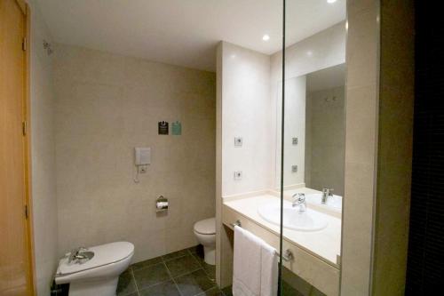 a bathroom with a toilet and a sink and a mirror at Alda Valladolid Sur in Valladolid