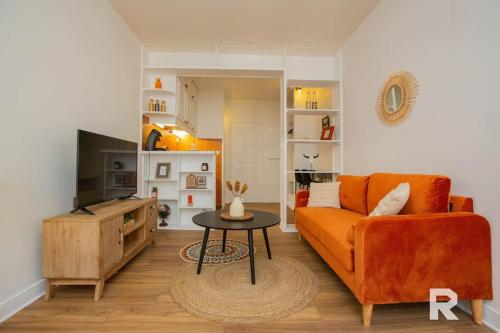 a living room with an orange couch and a table at Ô Centre- Chaleureux - Fibre - Netflix in Montargis