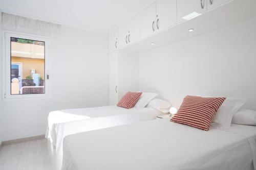 2 witte bedden in een witte kamer met een raam bij Cosy flat with sea views in Santa Ursula in Santa Úrsula