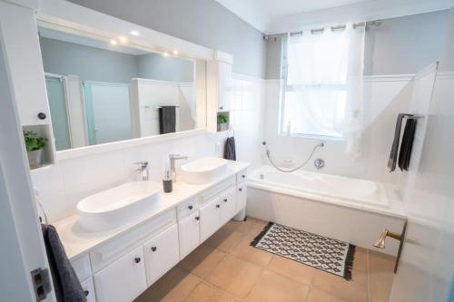 uma casa de banho com 2 lavatórios, uma banheira e um espelho. em Sole Haven em Southbroom