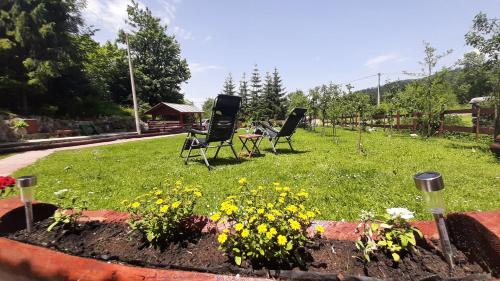 two chairs sitting in a garden with flowers at Chalet Woody in Stara Sušica