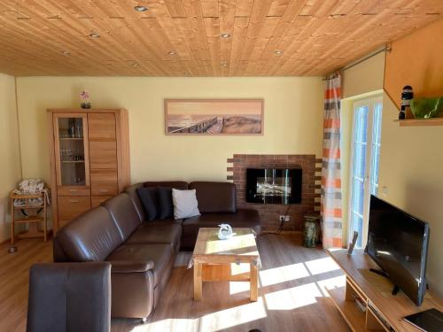 a living room with a leather couch and a fireplace at Holiday Home Strelasund by Interhome in Altefähr