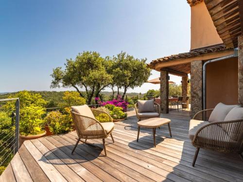 une terrasse en bois avec des chaises et des chaises. dans l'établissement Villa Le Pas de Courtin by Interhome, à Bormes-les-Mimosas