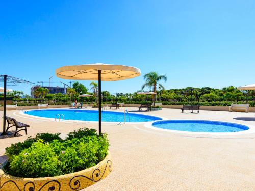 uma piscina com um guarda-sol, uma mesa e cadeiras em Apartment Sea View - Jardines del Mar I by Interhome em El Borseral