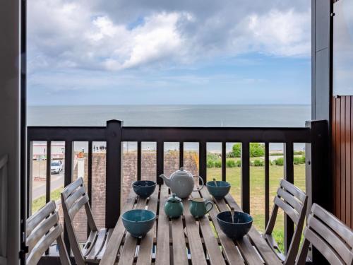 einen Tisch mit vier Tassen auf einem Balkon mit Meerblick in der Unterkunft Apartment La Bizontine by Interhome in Cabourg