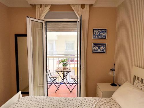a bedroom with a bed and a balcony with a table at Como en casa in Málaga