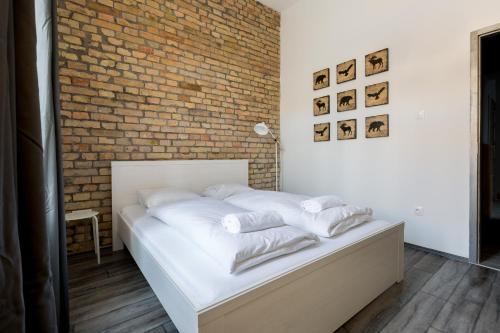 a bedroom with a white bed with a brick wall at J26 Jósika Apartment in Budapest