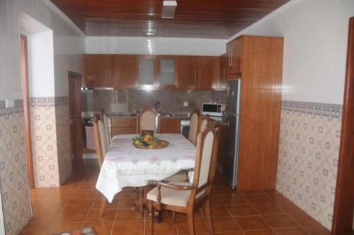a dining room with a table and chairs and a kitchen at Residência Teresinha in Povoação