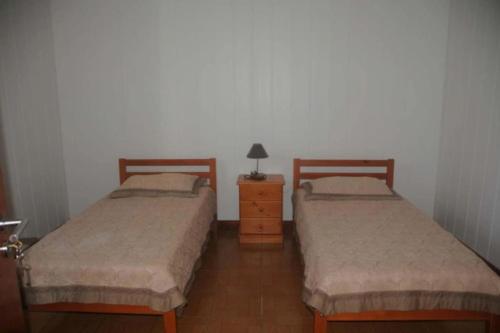 two twin beds in a room with a night stand and a lamp at Residência Teresinha in Povoação