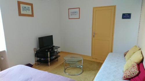 Cette chambre comprend un lit, une télévision et un tabouret. dans l'établissement Chambre d'hôte au pays des abers, à Lannilis