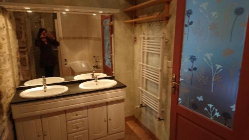 une femme prenant une photo d'une salle de bains avec deux lavabos dans l'établissement Chambre d'hôte au pays des abers, à Lannilis