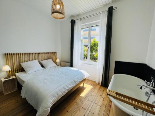une chambre avec un lit, une baignoire et un lavabo dans l'établissement Maison des années 1920 - à 150 m de l'océan et proche des commodités - 4 logements indépendants, à Saint-Jean-de-Monts