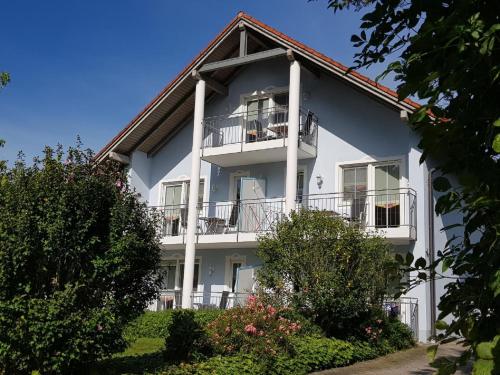 biały budynek apartamentowy z balkonem i drzewami w obiekcie Appartementhaus am Brückerl w mieście Bad Füssing