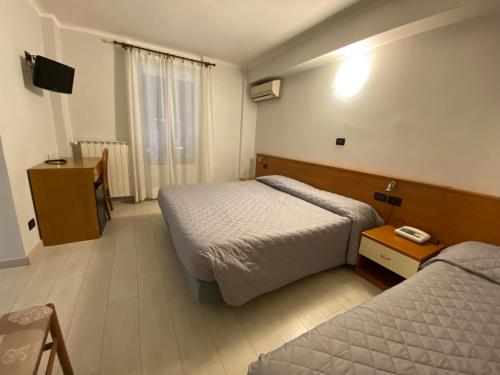a hotel room with two beds and a television at Albergo Fiorenza & Banksia Meublè in Alassio