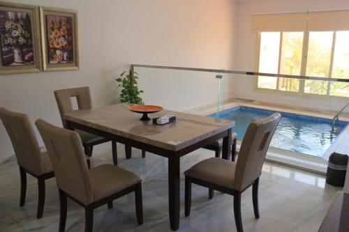 una sala da pranzo con tavolo, sedie e piscina di Al Wadi Touristic Resort a Al Shafa