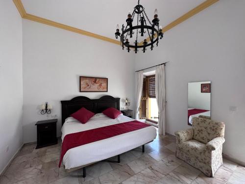 a bedroom with a bed and a chandelier and a chair at Hotel Bodega el Moral in Ribera del Fresno