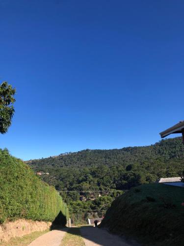 a road on a hill with a blue sky at Casa Aconchegante na Montanha in Campos do Jordão
