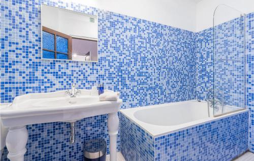 a blue tiled bathroom with a sink and a tub at 4 Bedroom Gorgeous Home In Magalas in Magalas