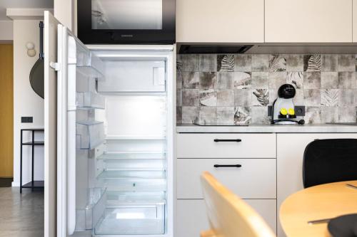 an empty refrigerator in a kitchen with a table at Bluetique Studio of Palanga in Palanga