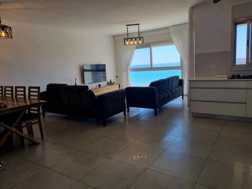 a living room with chairs and a table and a kitchen at Ducks on the beach in ‘Akko