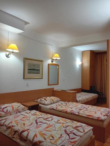 a hotel room with two beds and a mirror at Vila Centar in Trebinje