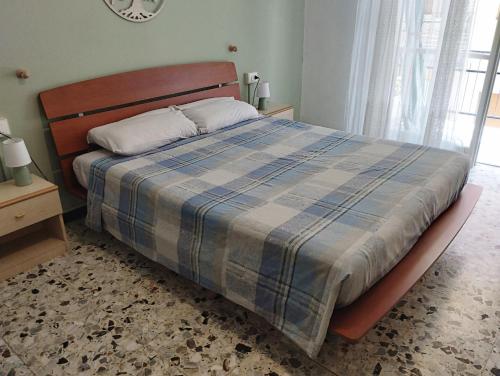 um quarto com uma cama com um cobertor xadrez azul em LOANO MARE em Loano