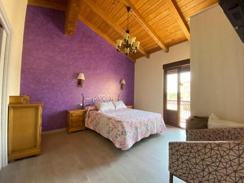 ein Schlafzimmer mit einem Bett und einer lila Wand in der Unterkunft Casa Amada con piscina in Murias de Pedredo