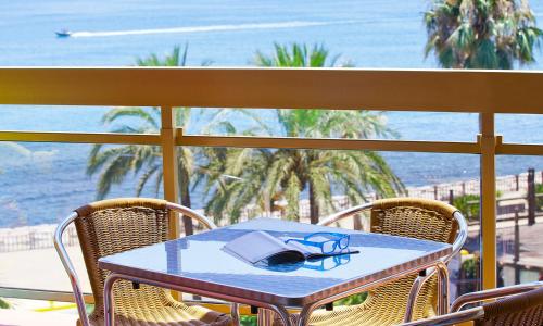 a table with glasses and a book on it on a balcony at 2 bedroom Penthouse Sea View Apartment within Sunset Beach Club in Benalmadena Costa