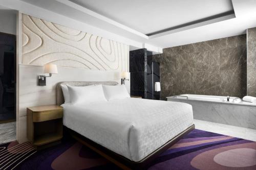 a bedroom with a white bed and a bath tub at Pasadena Hotel & Pool in Pasadena