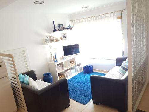 a living room with two chairs and a blue rug at Casa de Praia acolhedora/ Cosy beach house in Marinha das Ondas