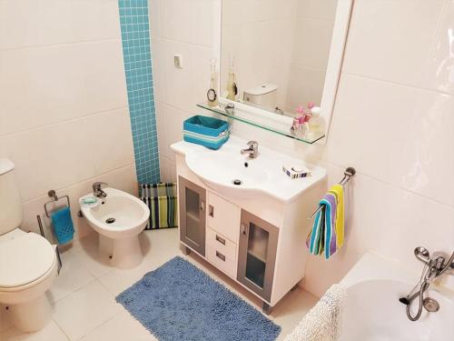 Casa de Praia acolhedora/ Cosy beach house في Marinha das Ondas: حمام مع حوض ومرحاض ومرآة