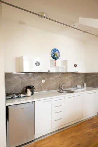 a kitchen with white cabinets and a sink at All Elevens 11 Apartments in Bitola
