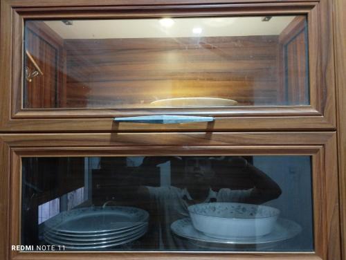 um reflexo de uma pessoa num armário com pratos em New White House em Colombo