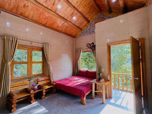 a bedroom with a red bed in a room with windows at A Sính Homestay in Ha Giang