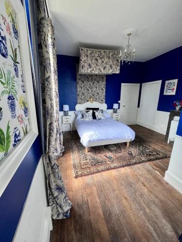 une chambre avec un lit aux murs bleus et au parquet dans l'établissement Maison de Mags & Mags Willow Room, à Lanouaille