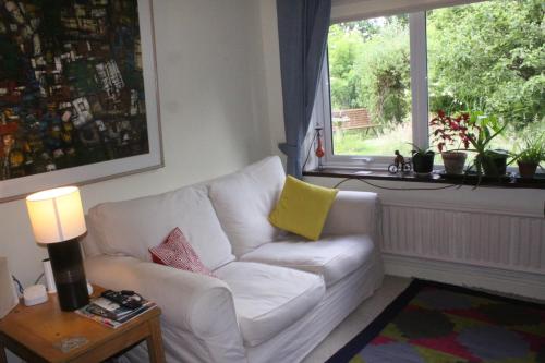 a living room with a white couch and a window at Sandford Meadow Guest House in Oxford
