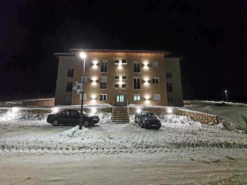two cars parked in front of a building at night at Apartman Mandić Žabljak in Žabljak