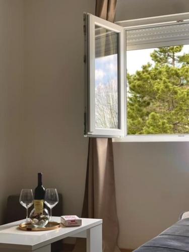 a table with wine glasses and a window at Apartman Mandić Žabljak in Žabljak
