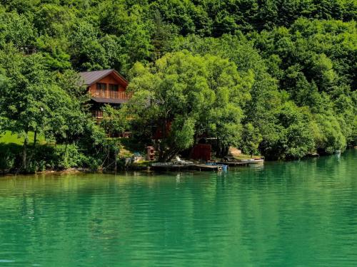 a house on the shore of a lake with trees at Forest Dream Lake House in Jajce