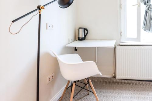 een bureau en een witte stoel in een kamer met een lamp bij Elegant Studio Flat 5 min to Moda Shore in Istanbul