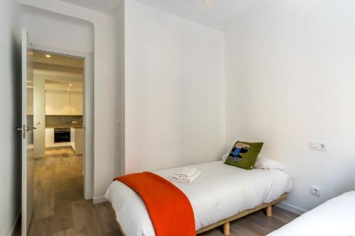 een witte slaapkamer met een bed met een oranje deken bij Bright Modern - 2Bedrooms 1Bathroom - Delicias in Madrid