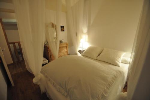 a bedroom with a white bed with curtains at Ferme Saint Joseph in Le Fousseret