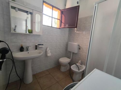 łazienka z umywalką, toaletą i oknem w obiekcie villetta immersa nel verde w mieście Galatone