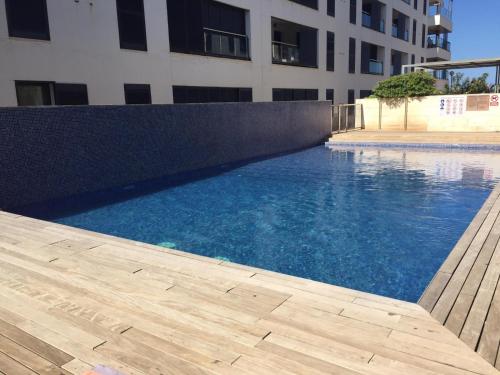 a swimming pool in front of a building at apartamento amplio en planta baja con terraza CALA BUSQUETS in Ciutadella