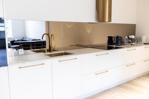 a kitchen with white cabinets and a sink at Srebrna Luxury Apartments - willa fabrykancka - wnętrza premium in Łódź