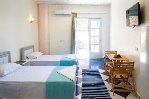 een hotelkamer met 2 bedden, een tafel en een televisie bij White Flat Studios in Dahab