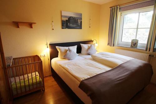 ein Schlafzimmer mit einem Bett, einem Fenster und einem Kinderbett in der Unterkunft Seerose in Bliesdorf